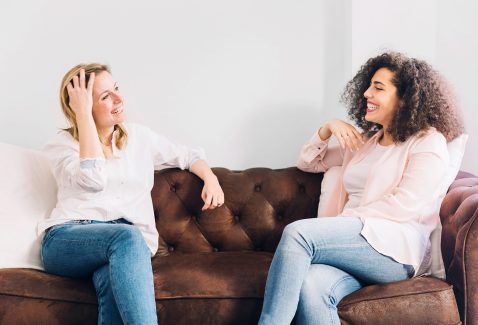 cheerful-women-talking-sofa